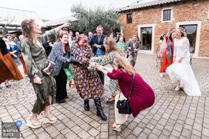Wedding celebration on outdoor brick patio with guests in festive attire.