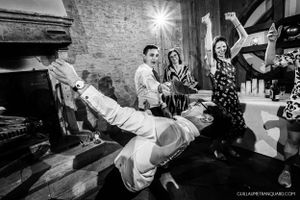 Black and white image of dancers performing dynamic moves at a stone-walled venue.