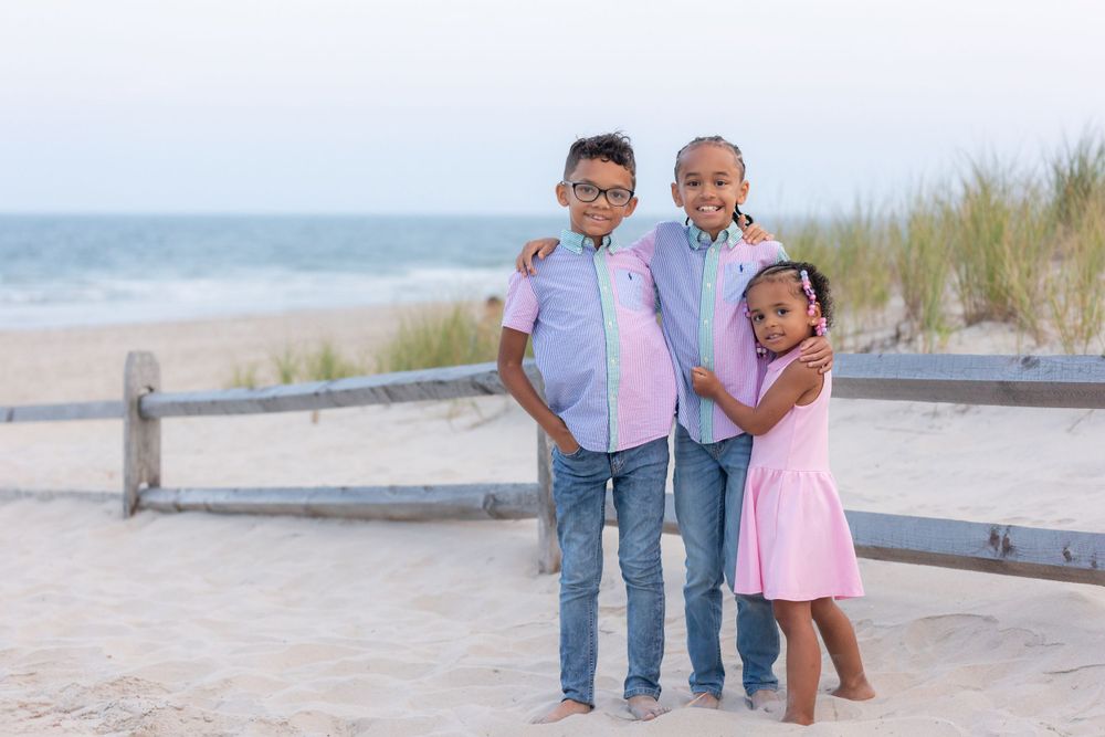 three children standing in front of a fence on the dunes at 58th street beach in ocean city new jersey