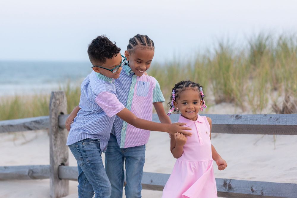 three children standing in front of a fence on the dunes at 58th street beach in ocean city new jersey