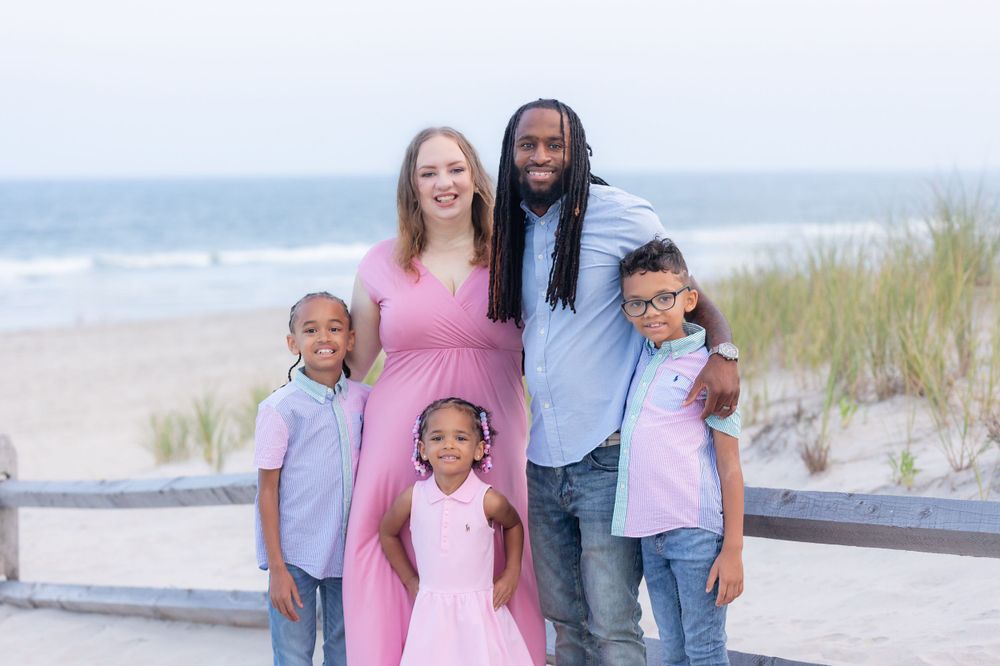 family of five standing in front of a fence on the dunes at 58th street beach in ocean city new jersey