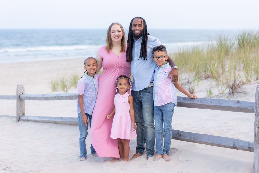 family of five standing in front of a fence on the dunes at 58th street beach in ocean city new jersey