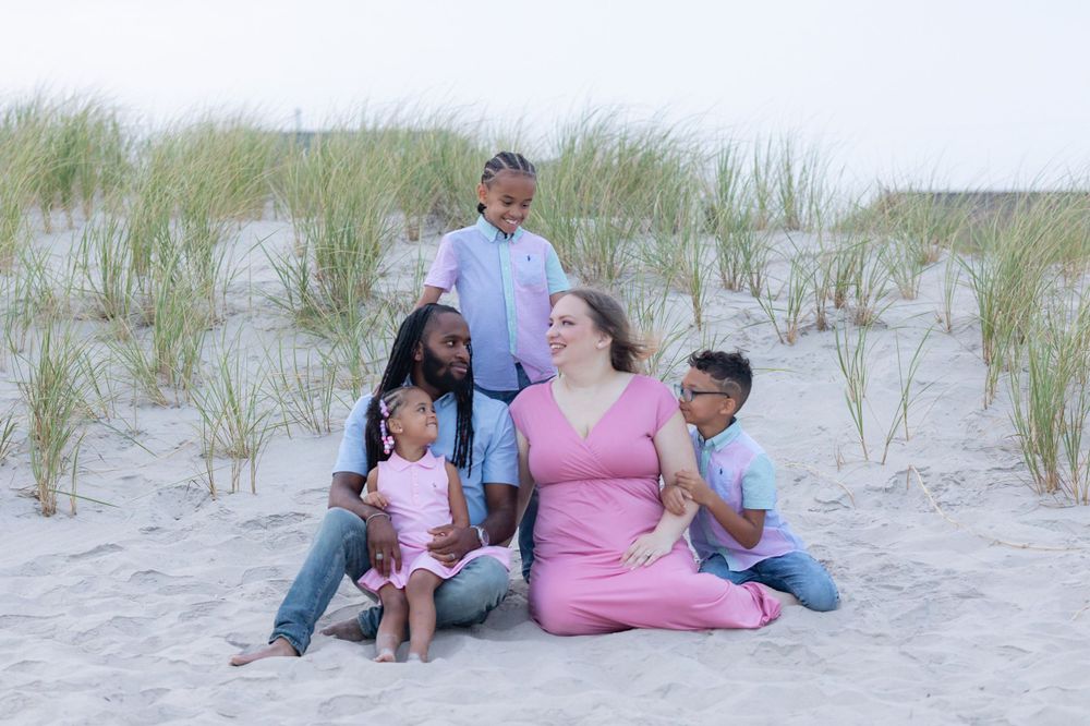 a family of five sitting in the sand in front of the dunes at 58th street beach in ocean city new jersey