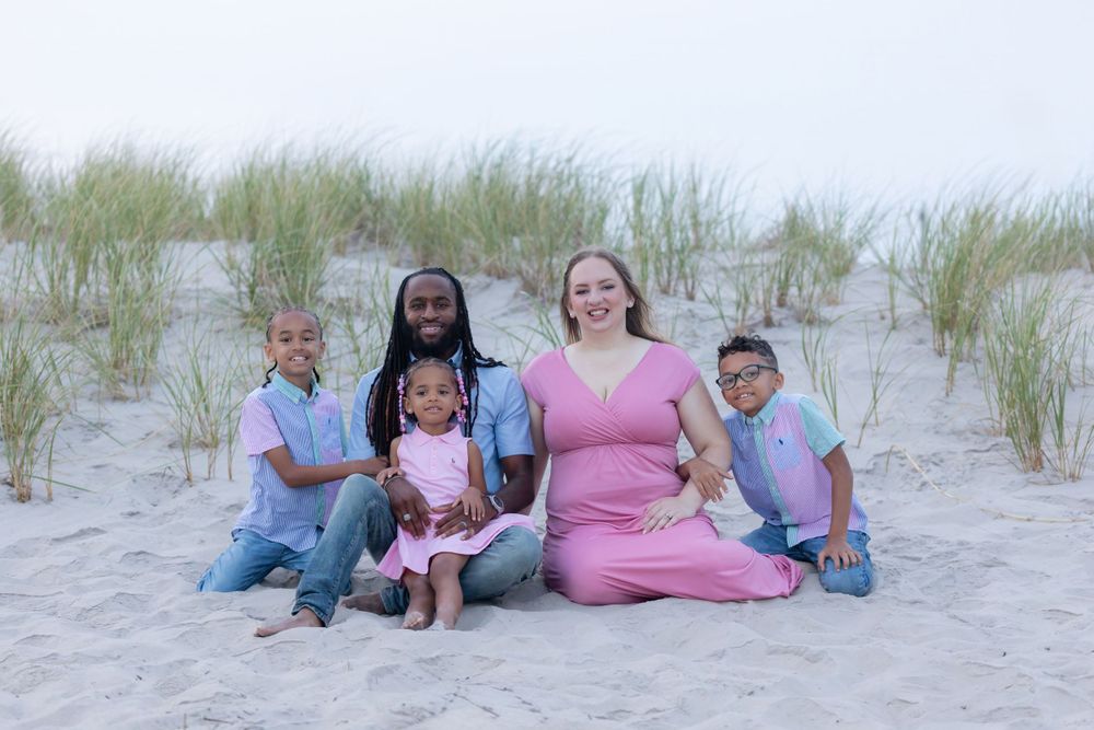 a family of five sitting in the sand in front of the dunes at 58th street beach in ocean city new jersey