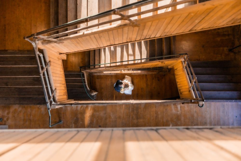 A dramatic aerial view of a spiral staircase with wedding dress forming patterns below.