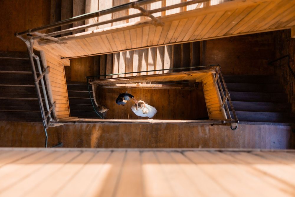 A creative perspective of a bride on a spiral staircase viewed from the top level.