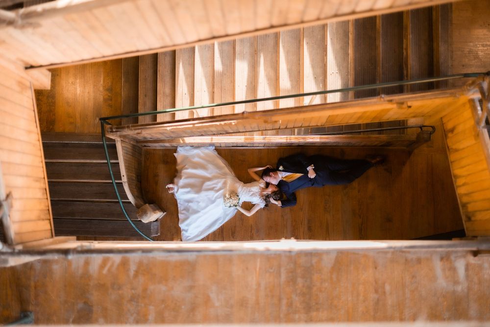 A spiral staircase view from above showing a wedding dress flowing down the steps.
