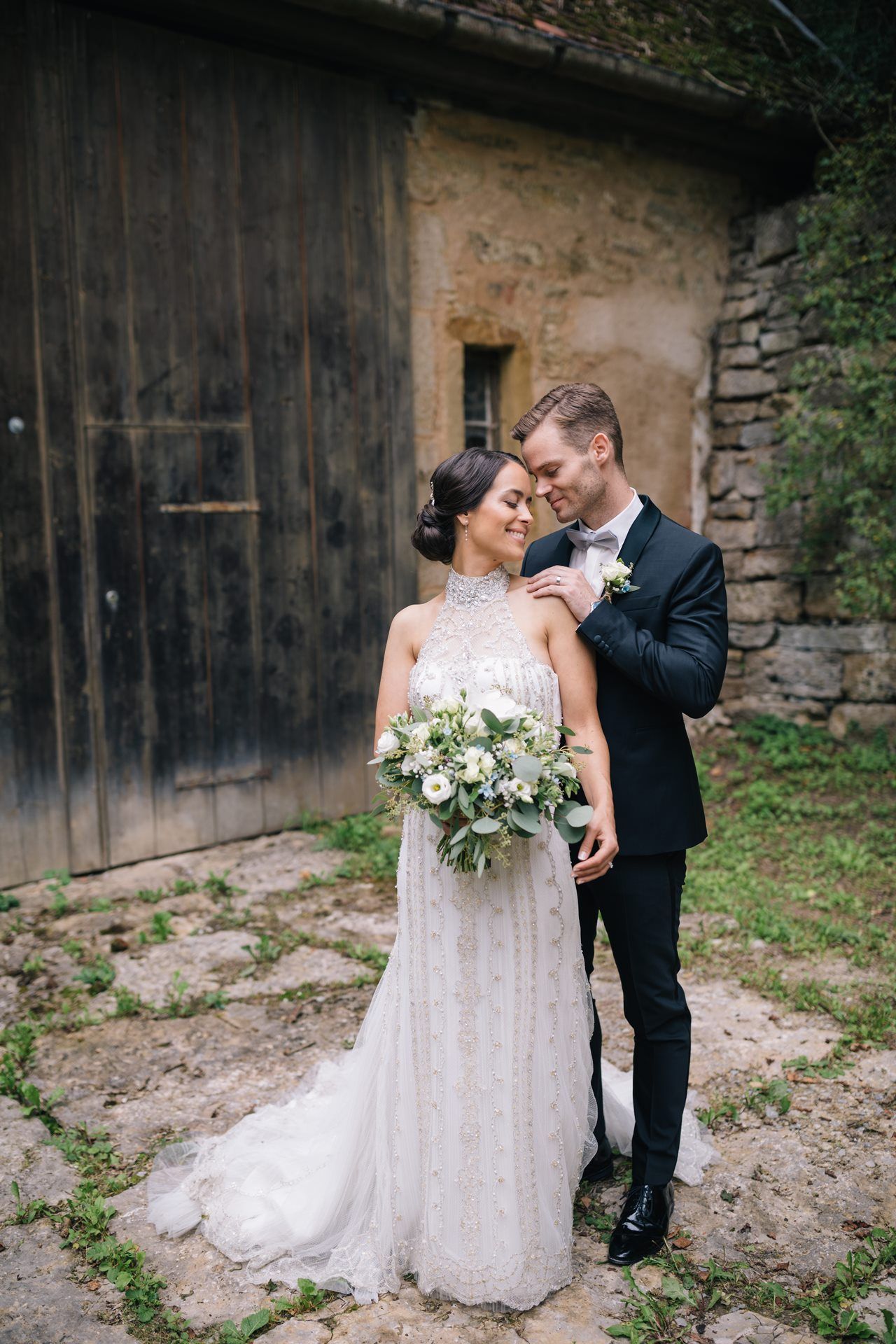 Hochzeitsfotografie - Brautpaar in enger Pose vor alter Holzwand. Rothenburg ob der Tauber Wildbad.