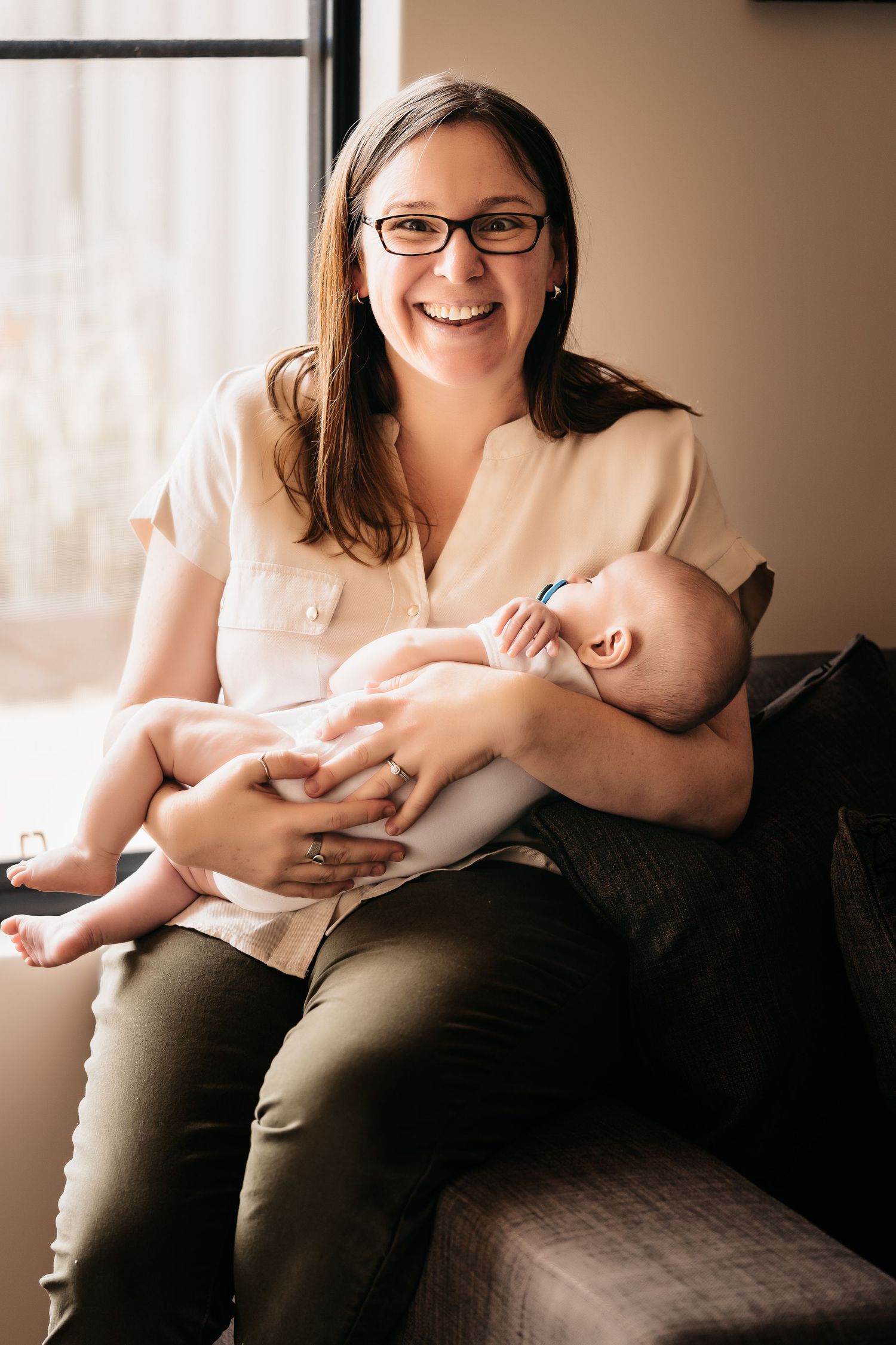 A tender moment between parent and baby while sitting on a cozy couch by a window.