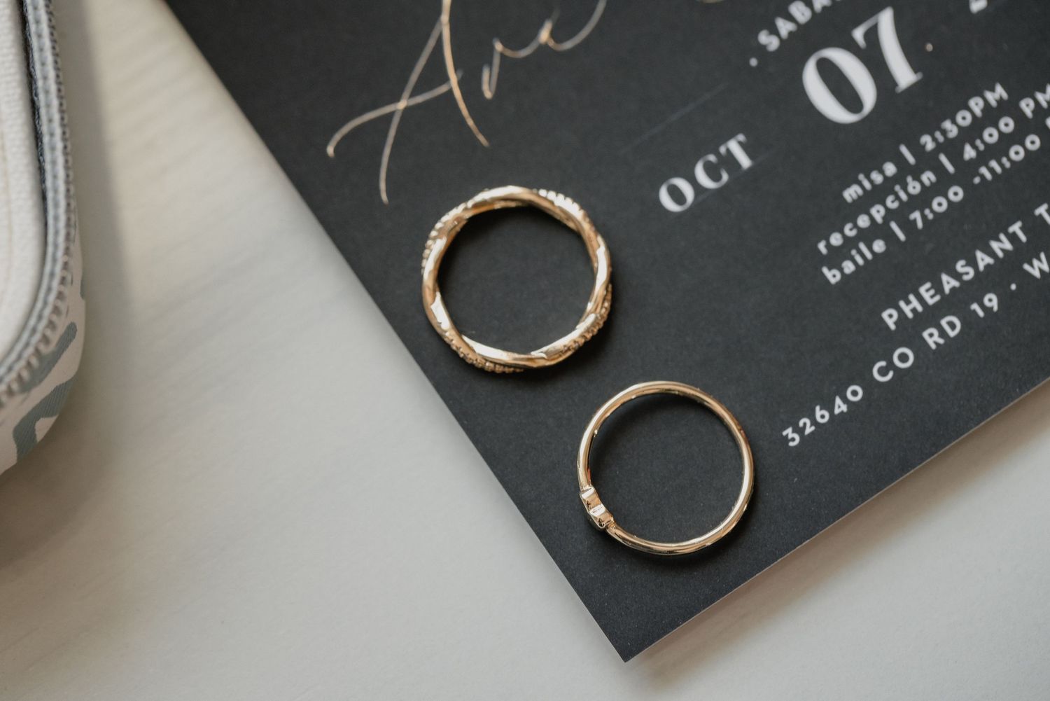 Two gold wedding rings photographed on black invitation card.