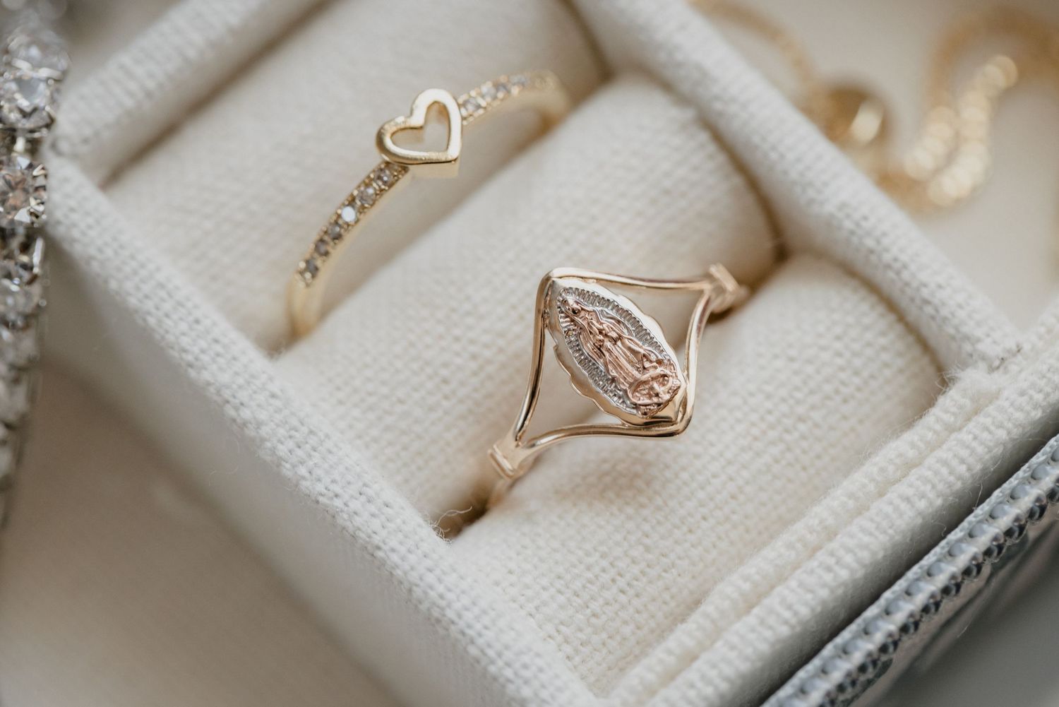 Delicate rose gold rings with heart and diamond designs in white jewelry box.