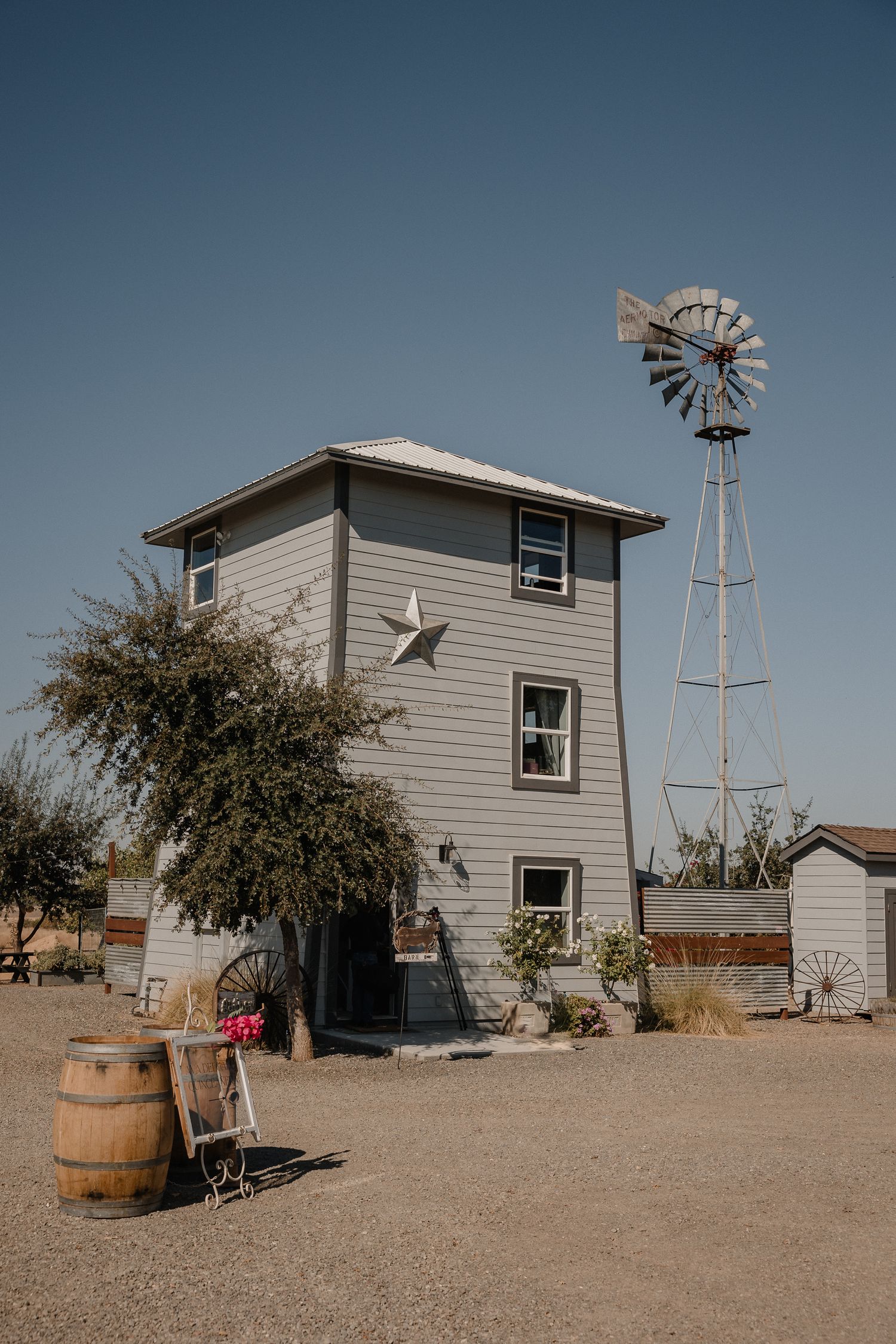 Rustic three-story house with star decoration and vintage windmill against a desert backdrop.