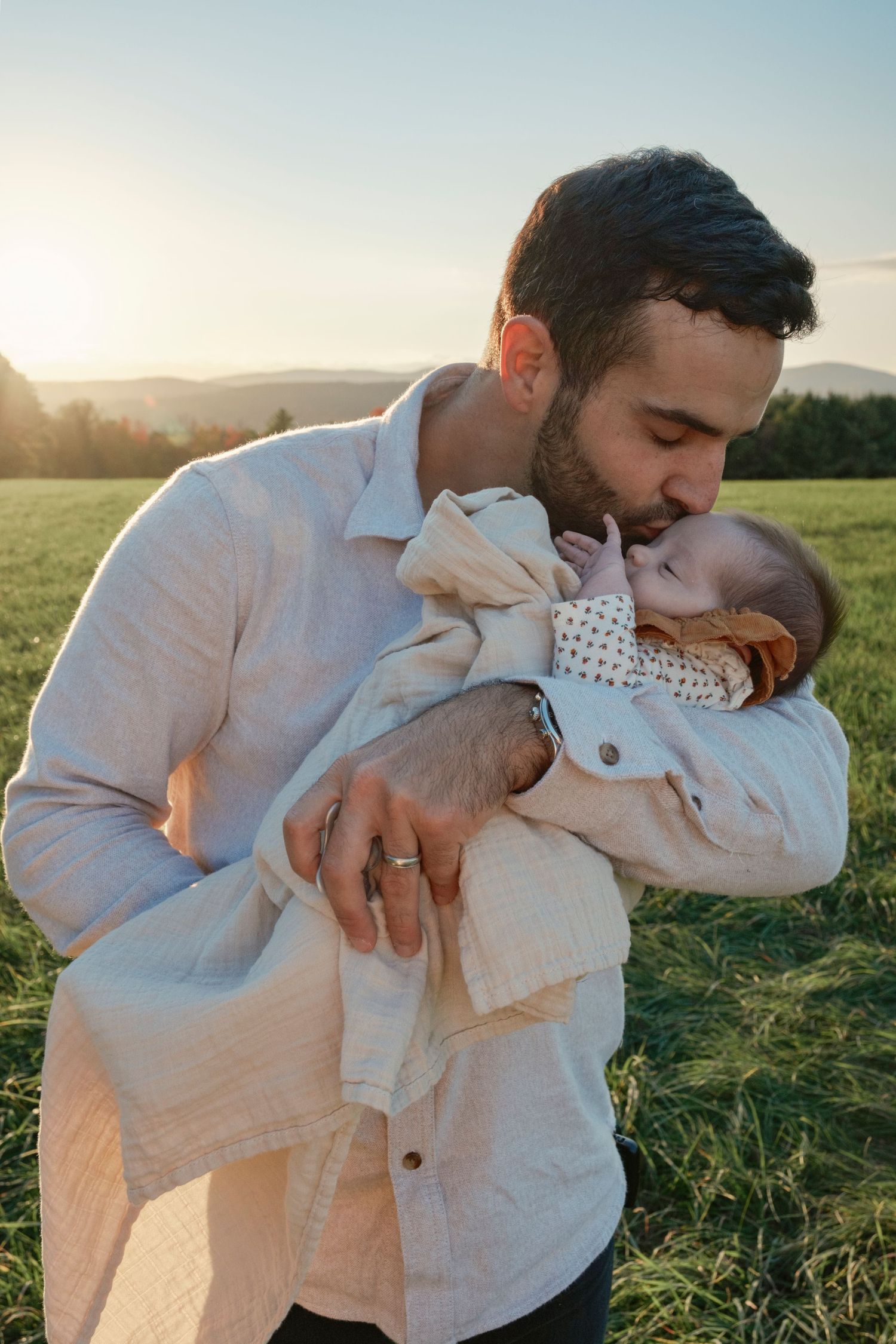 man kissing child in front of mountains