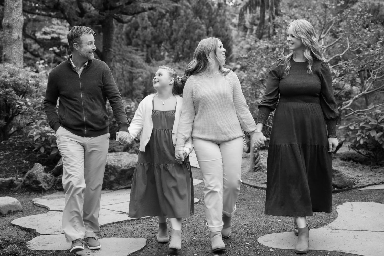 A black and white image showing four people walking together on a stone path.