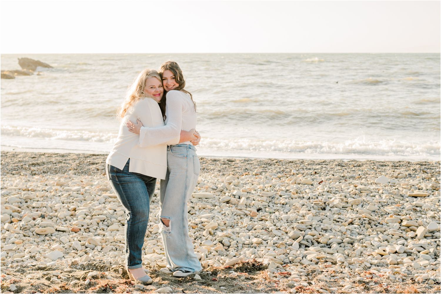 mom and teen daughter wearing white and denim for family photos on the beach