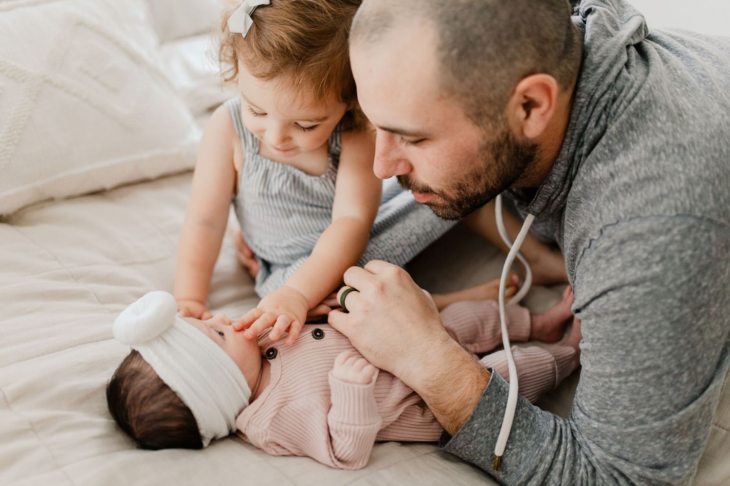 Intimate family lifestyle photos captured on a bed in muted tones.