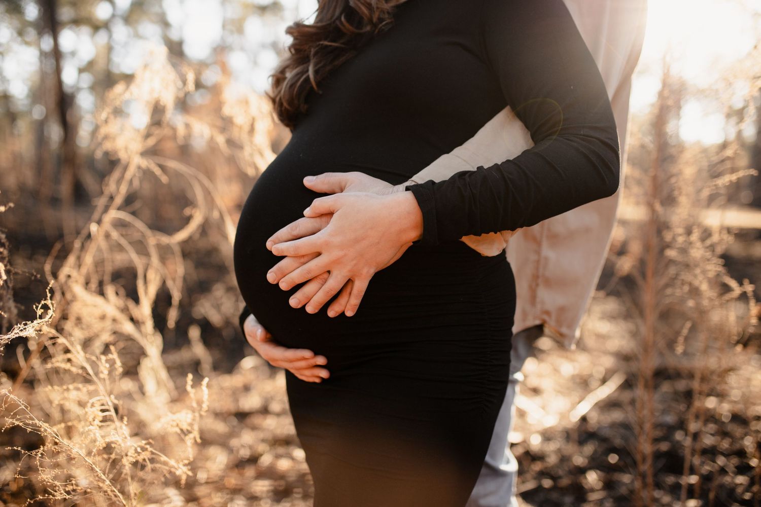 Maternity photo series captured in golden sunlight outdoors.