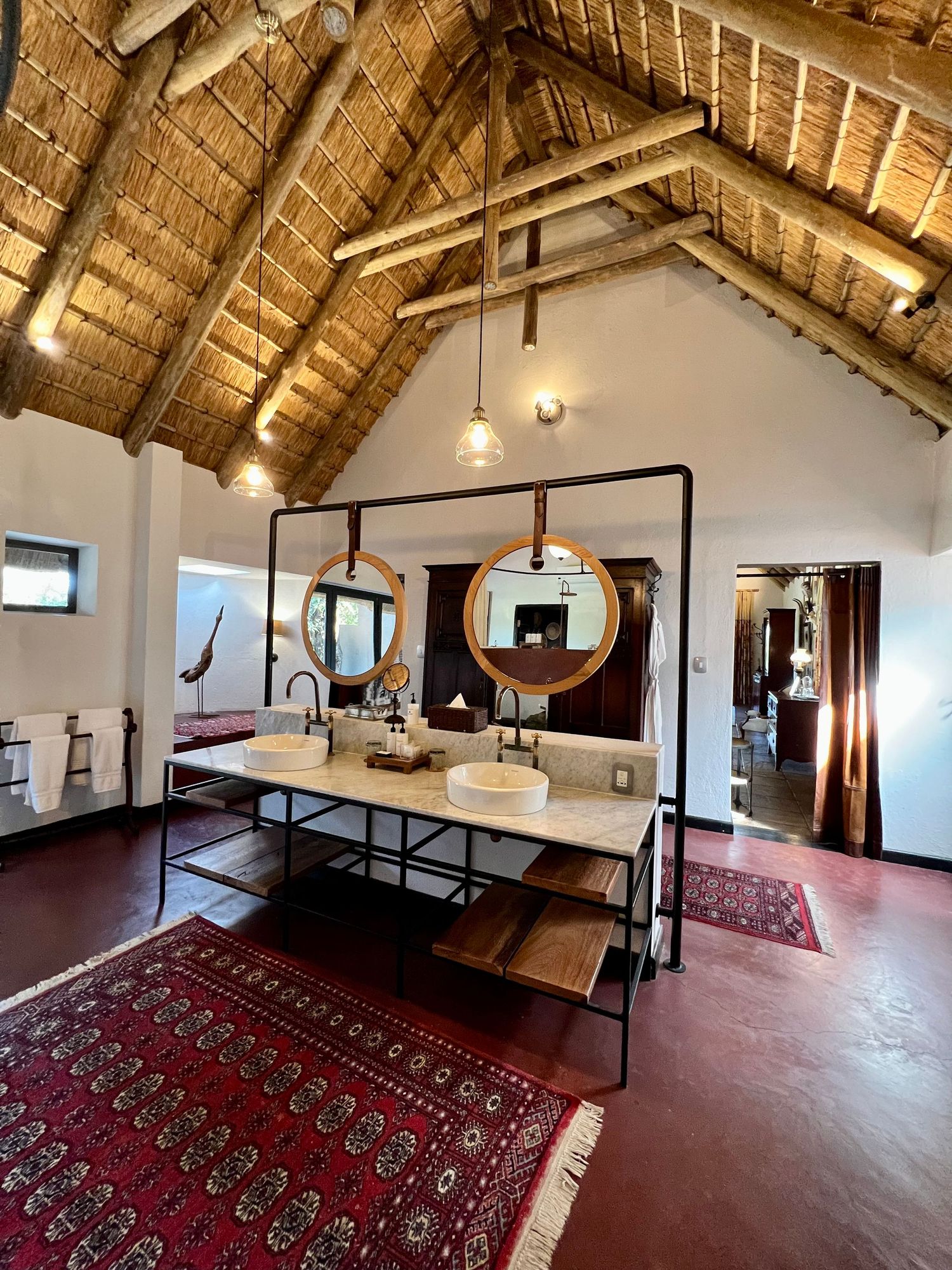 Spacious loft-style room with exposed wooden beams, oriental rugs, and modern furniture under vaulted ceilings.