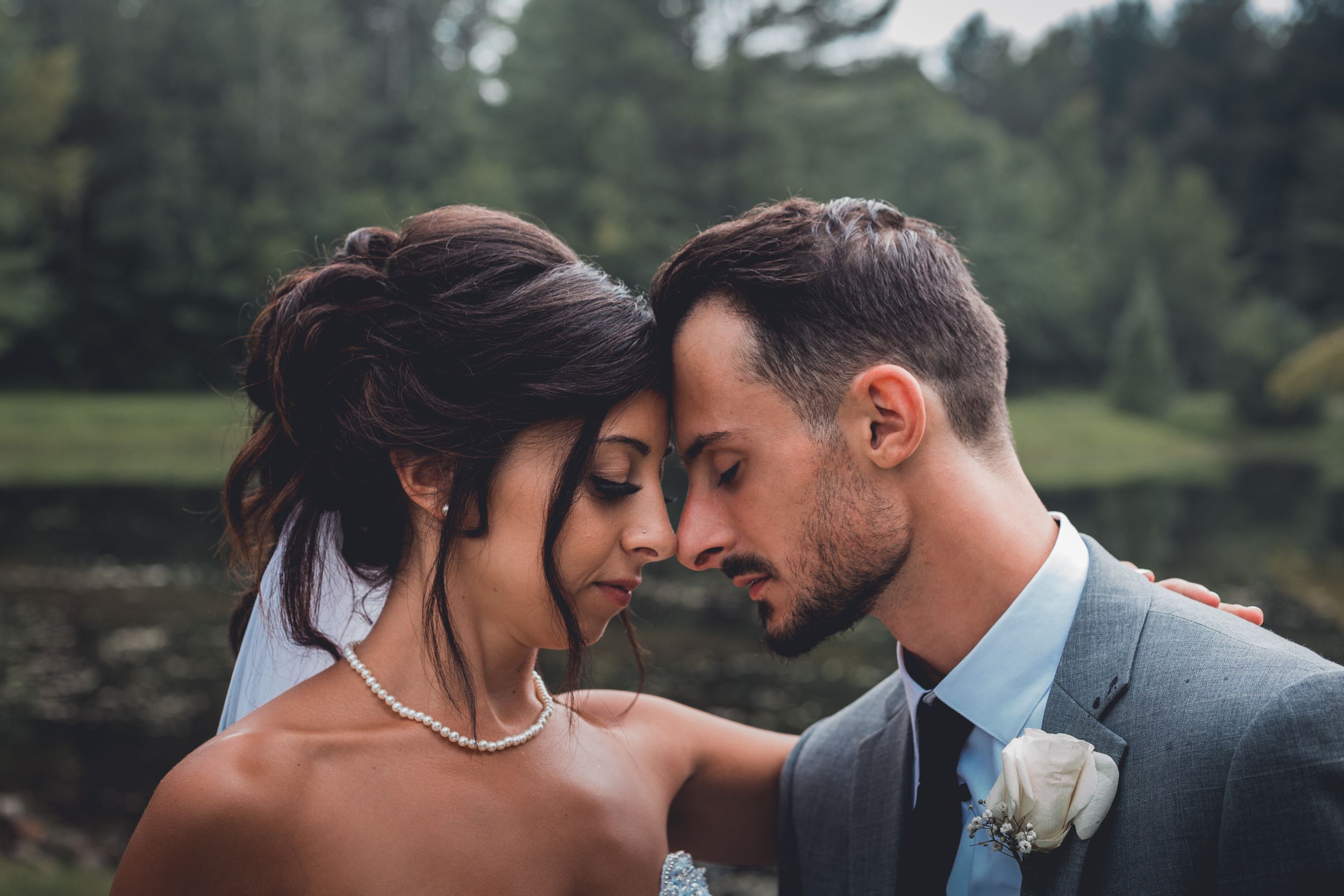 Intimate wedding portrait with couple sharing tender moment outdoors.