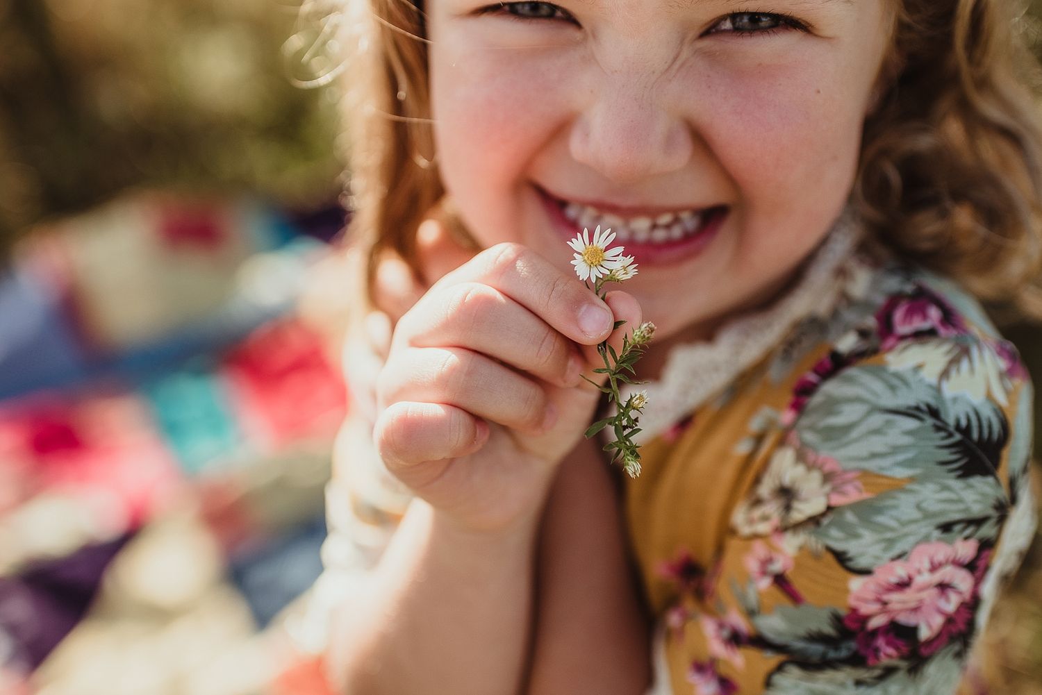 A close-up shot showing pure joy and laughter while holding a small flower.