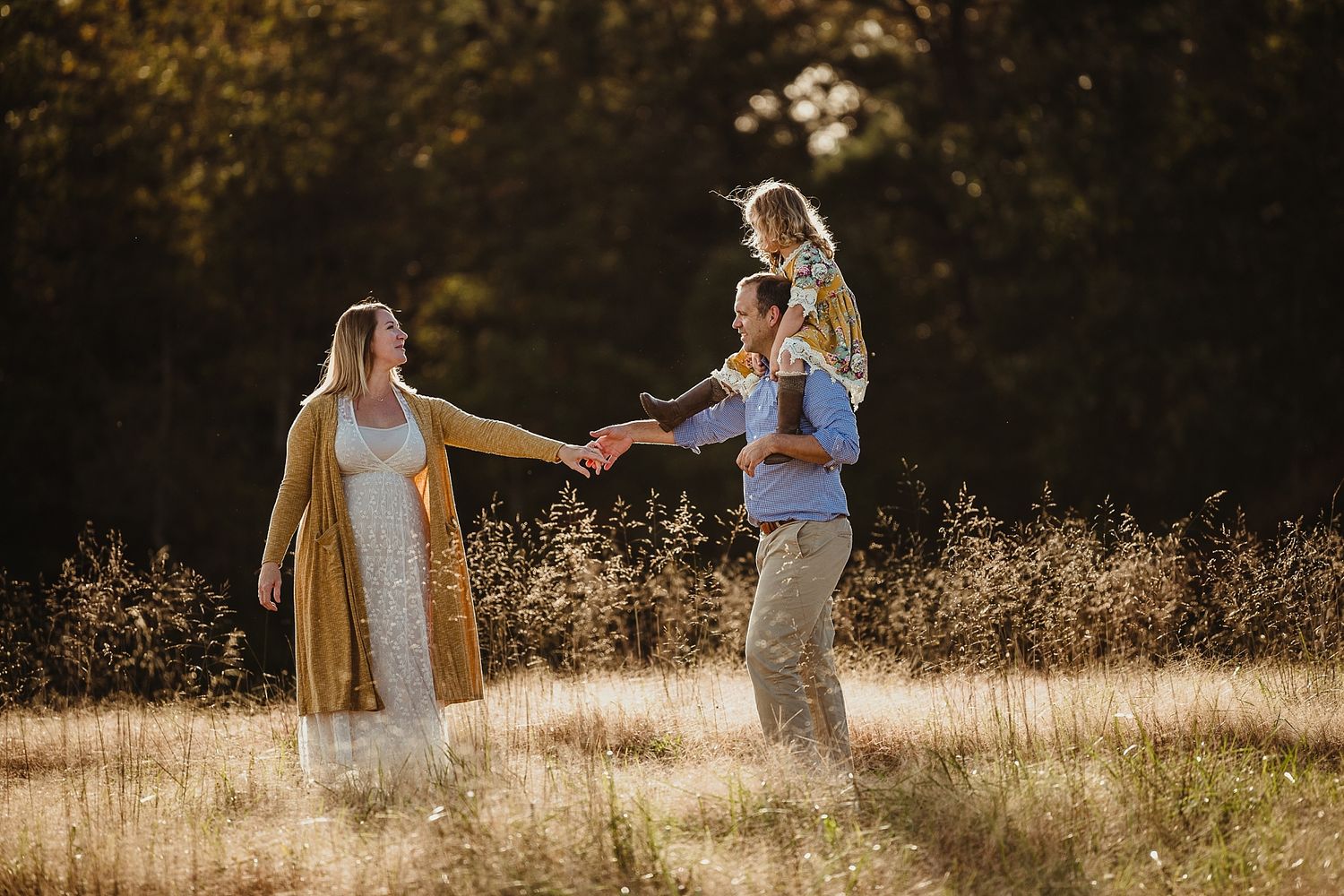 A sun-drenched family moment in a golden field during sunset.