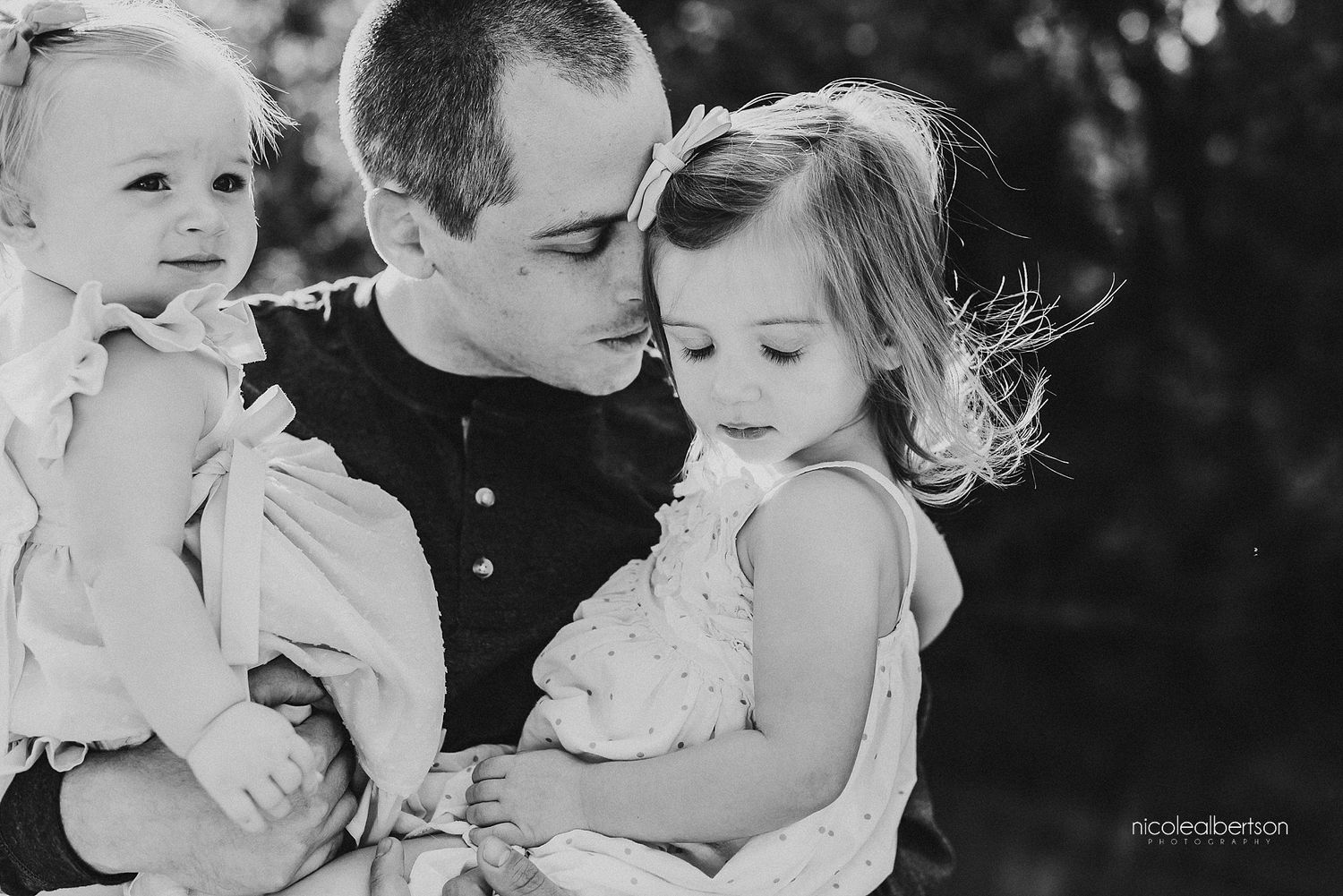 Tender black and white portrait of parent with children sharing an intimate moment.
