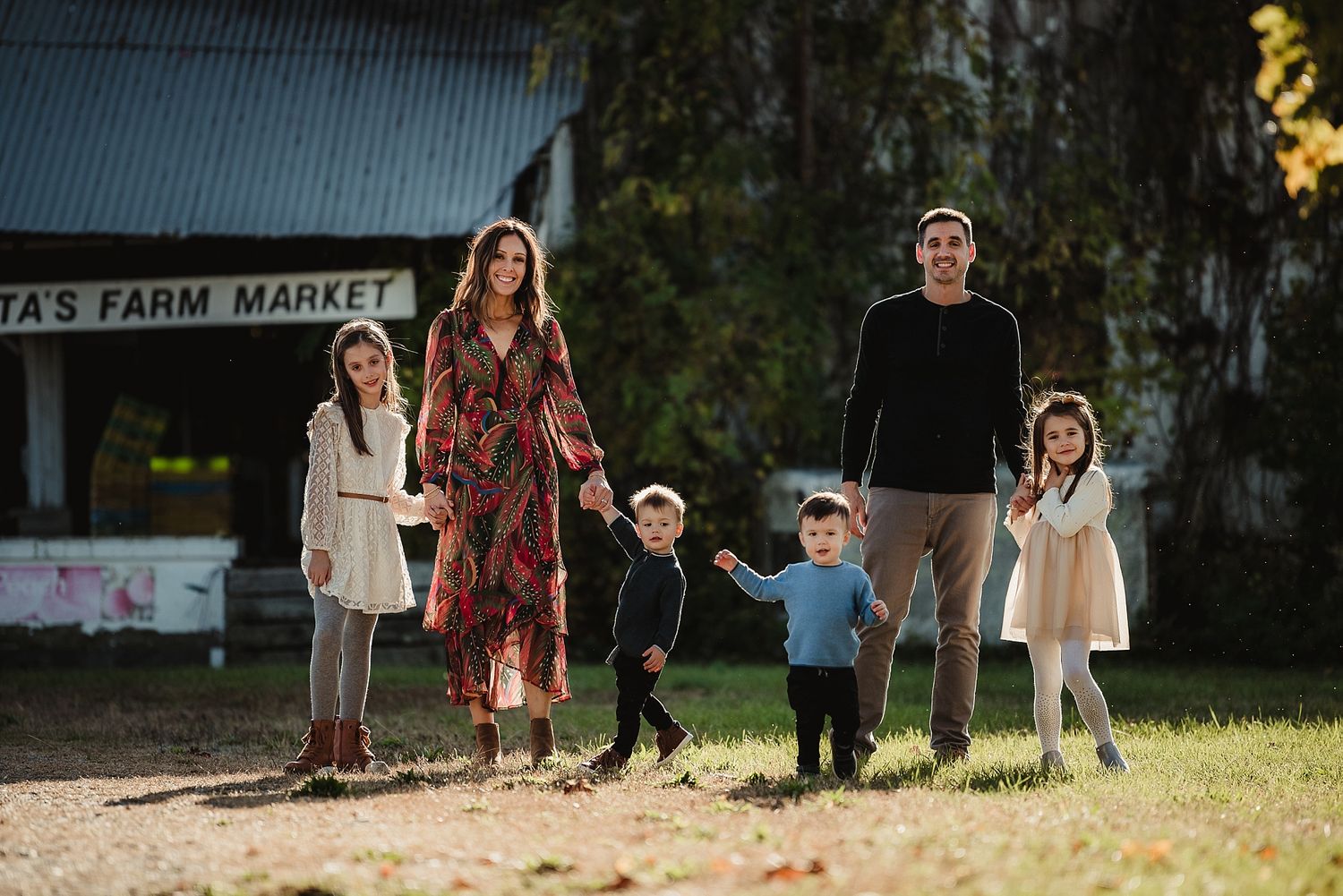 Group portrait of family standing together outside rustic farm market building.