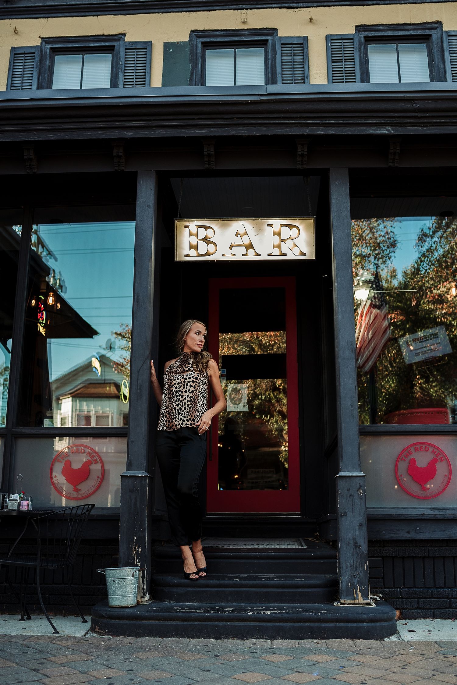 Stylish portrait at entrance of bar with vintage signage and red door.