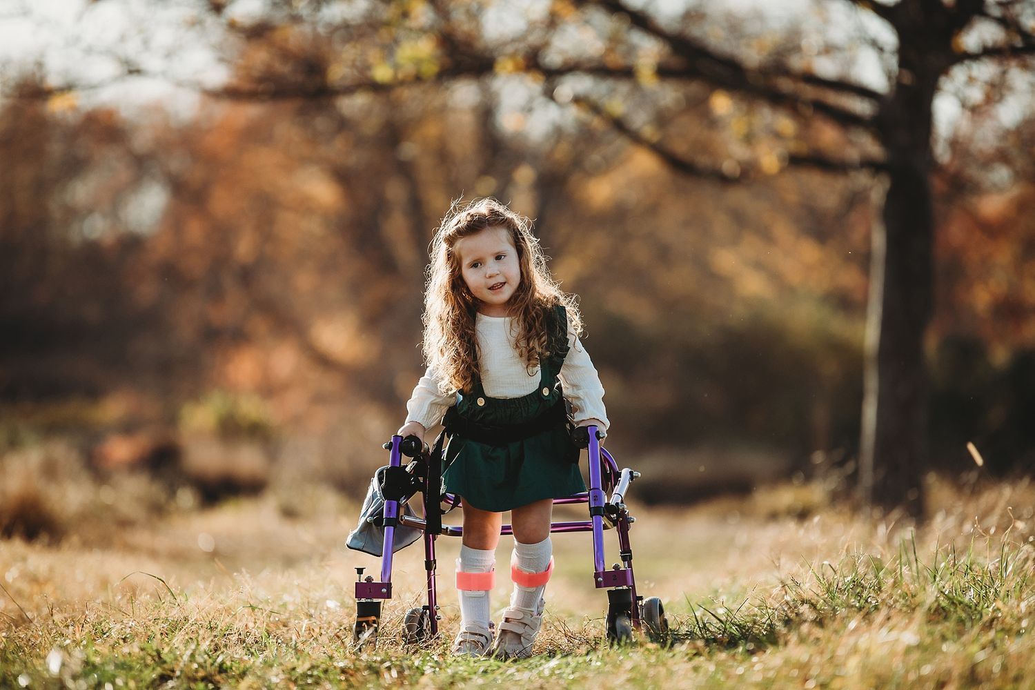 Young person with mobility walker poses confidently in autumn setting.