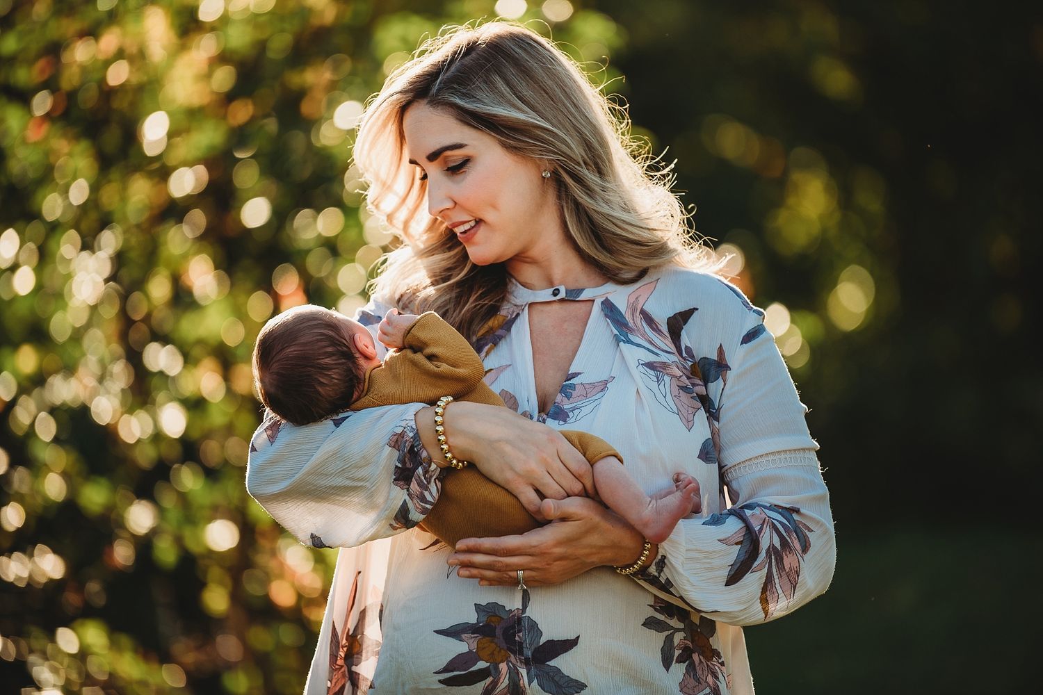 Tender moment captured in golden sunlight as parent cradles newborn baby.