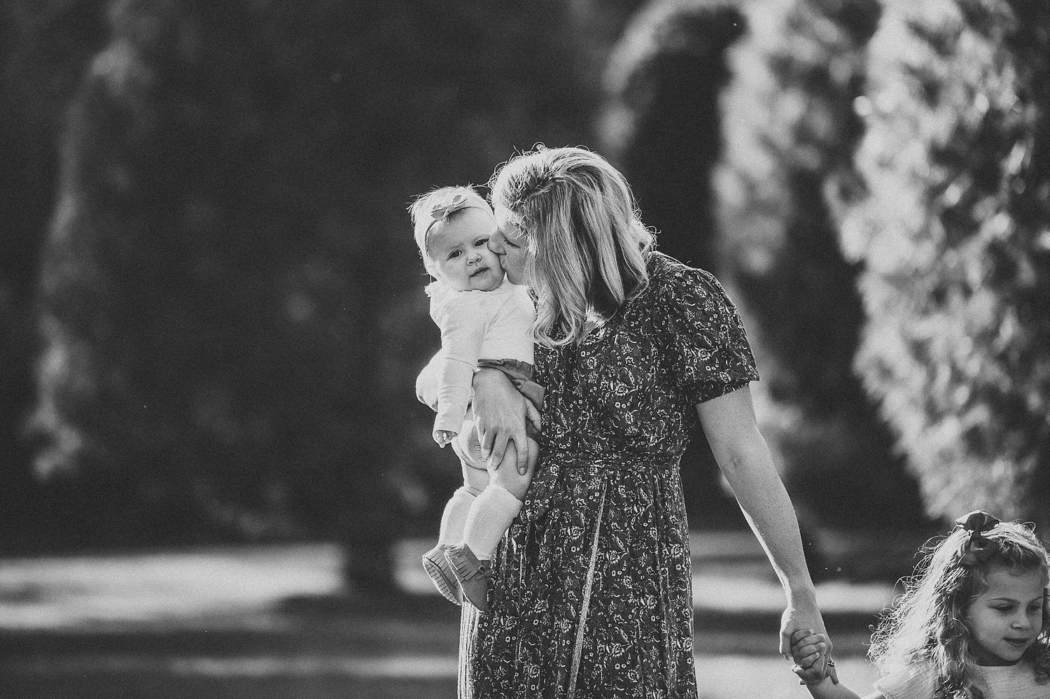 Black and white portrait of family moment outdoors among trees.