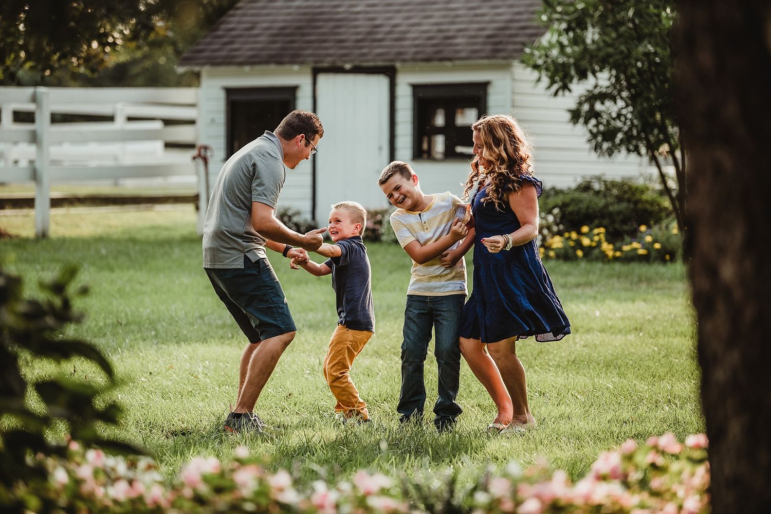 A family playing and dancing together on their lawn in front of a white house.