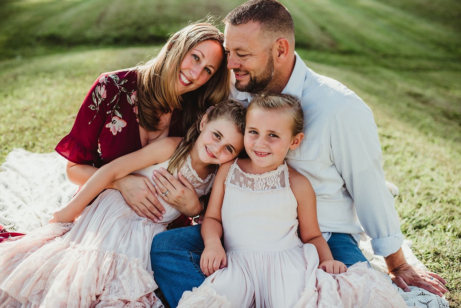 A family portrait on grass with everyone wearing coordinated burgundy and white outfits.