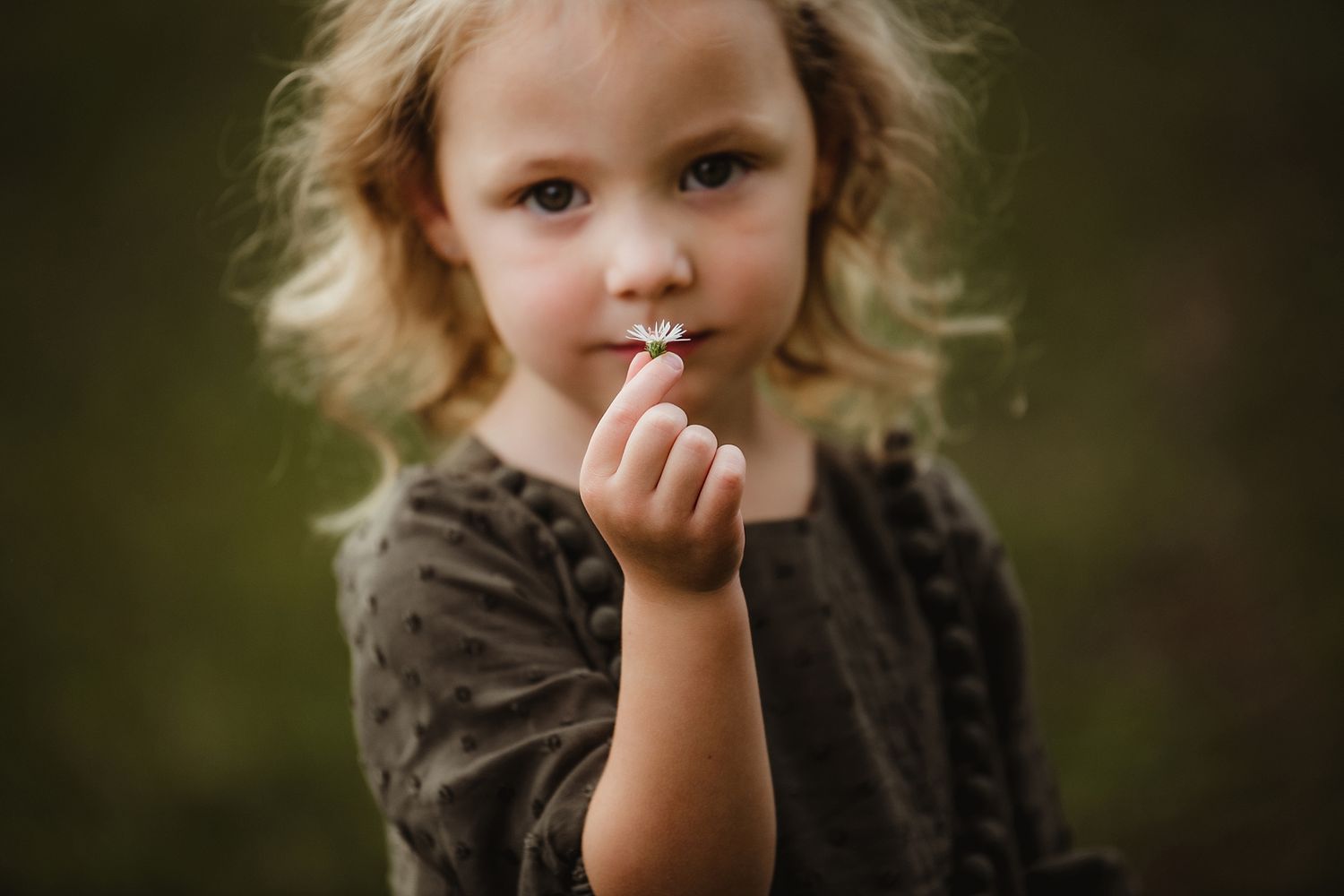 Portrait of a child with blonde curly hair in a dark sweater with soft natural lighting.