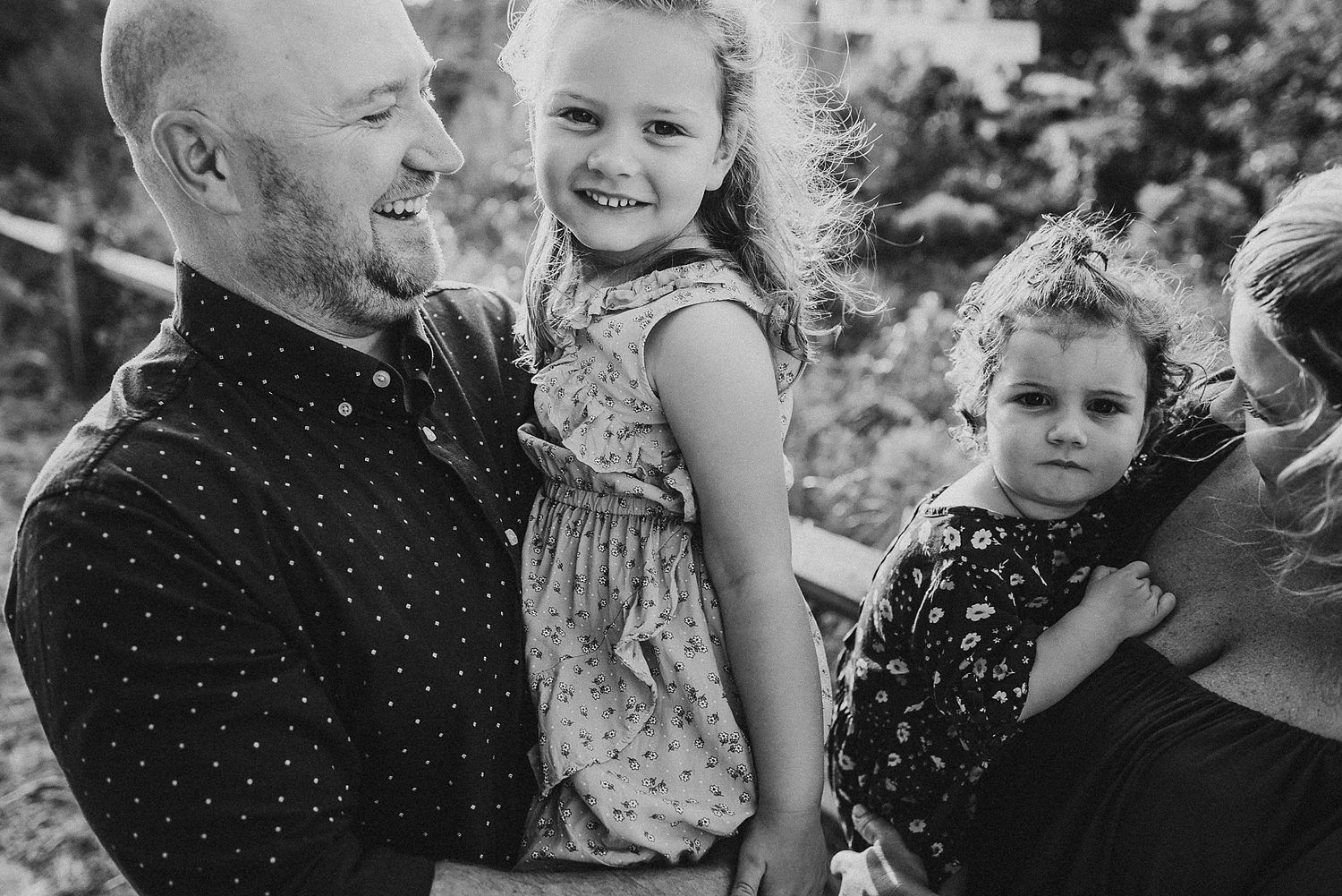 Black and white family portrait outdoors with children and adults together.