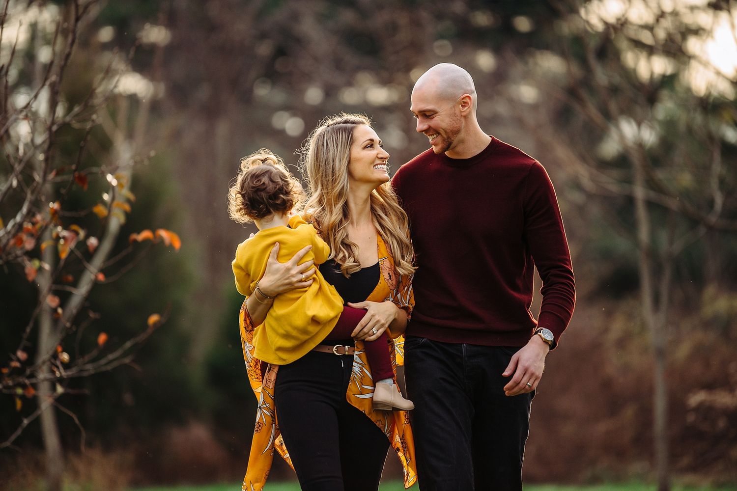Family portrait in autumn featuring warm burgundy and yellow tones against natural backdrop.