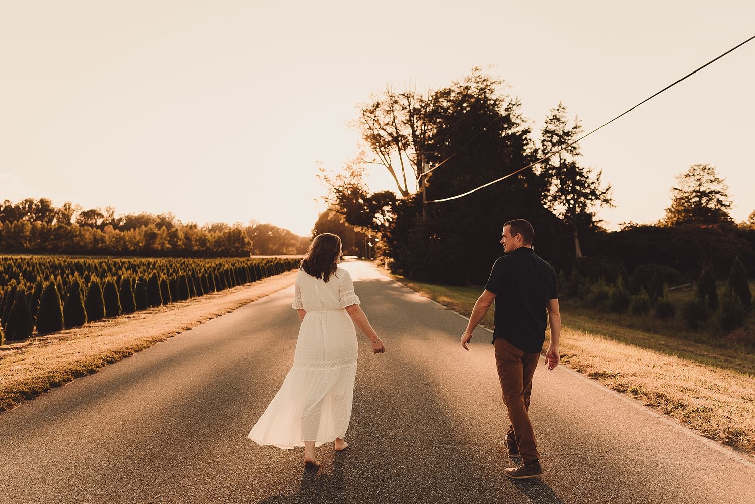 Couple holding hands while walking down a country road at sunset.