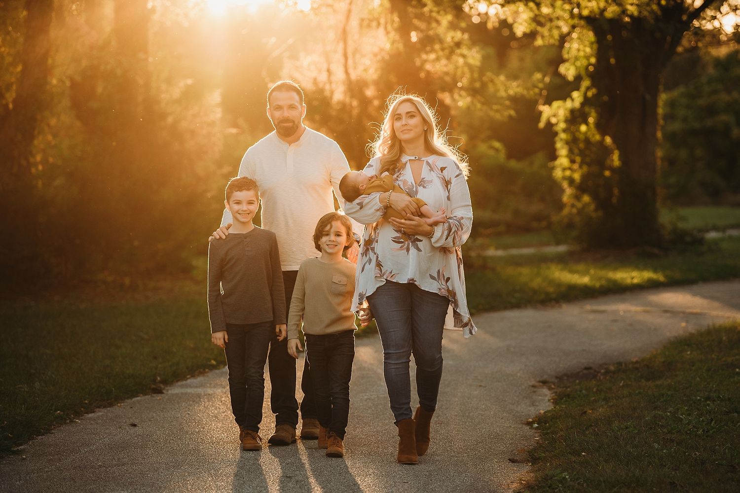 Family walking together on a path during golden hour with sunlight streaming behind them.