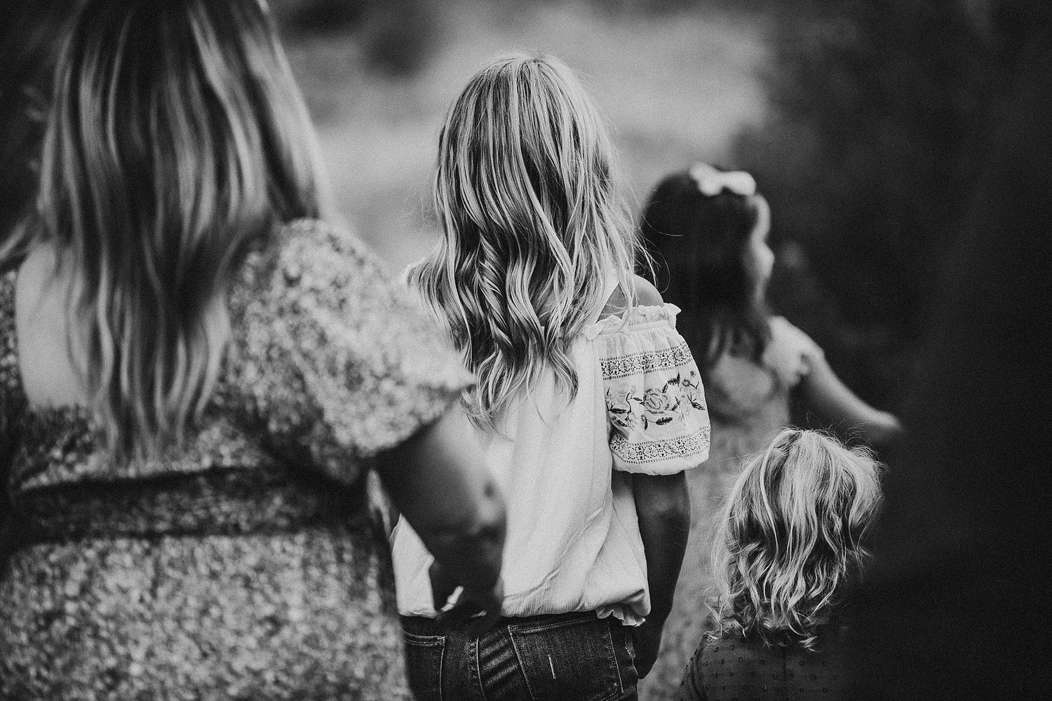 Black and white portrait of several people walking together with long hair flowing in breeze.
