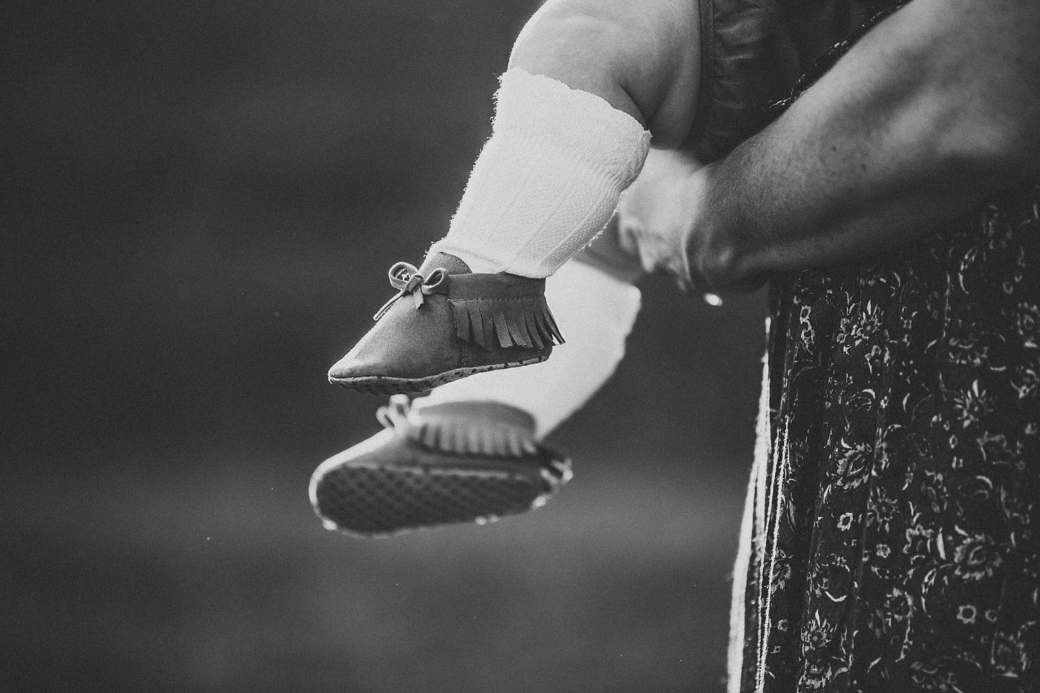 Close-up black and white shot of tiny baby shoes on feet.