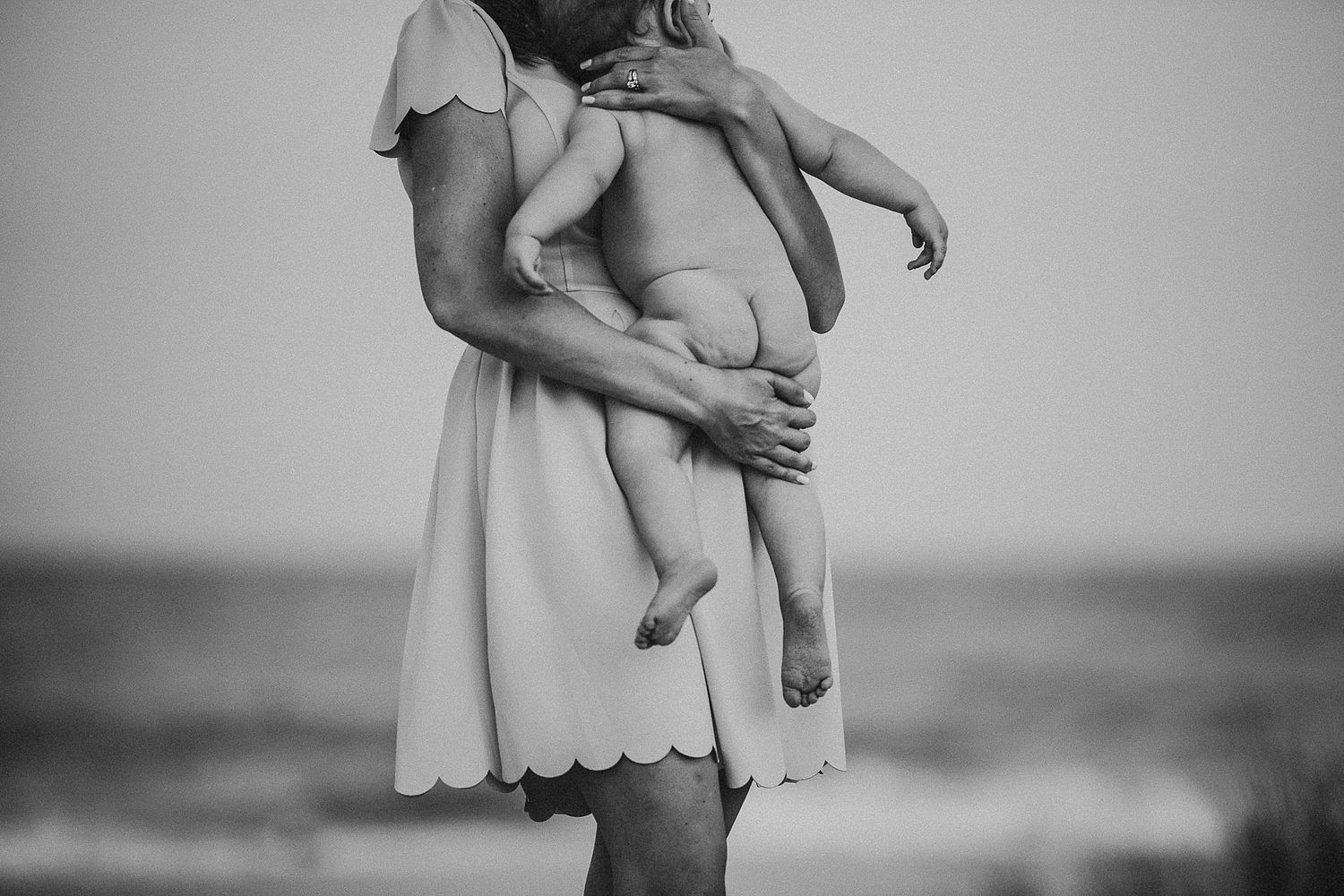 Black and white portrait of tender mother-child moment by the ocean.