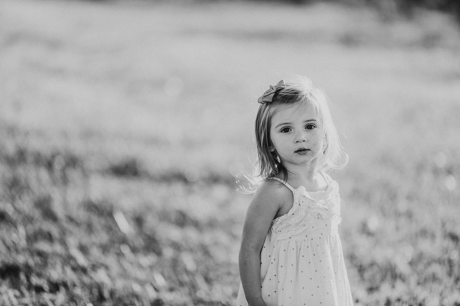 Black and white portrait of young child in sundress outdoors.