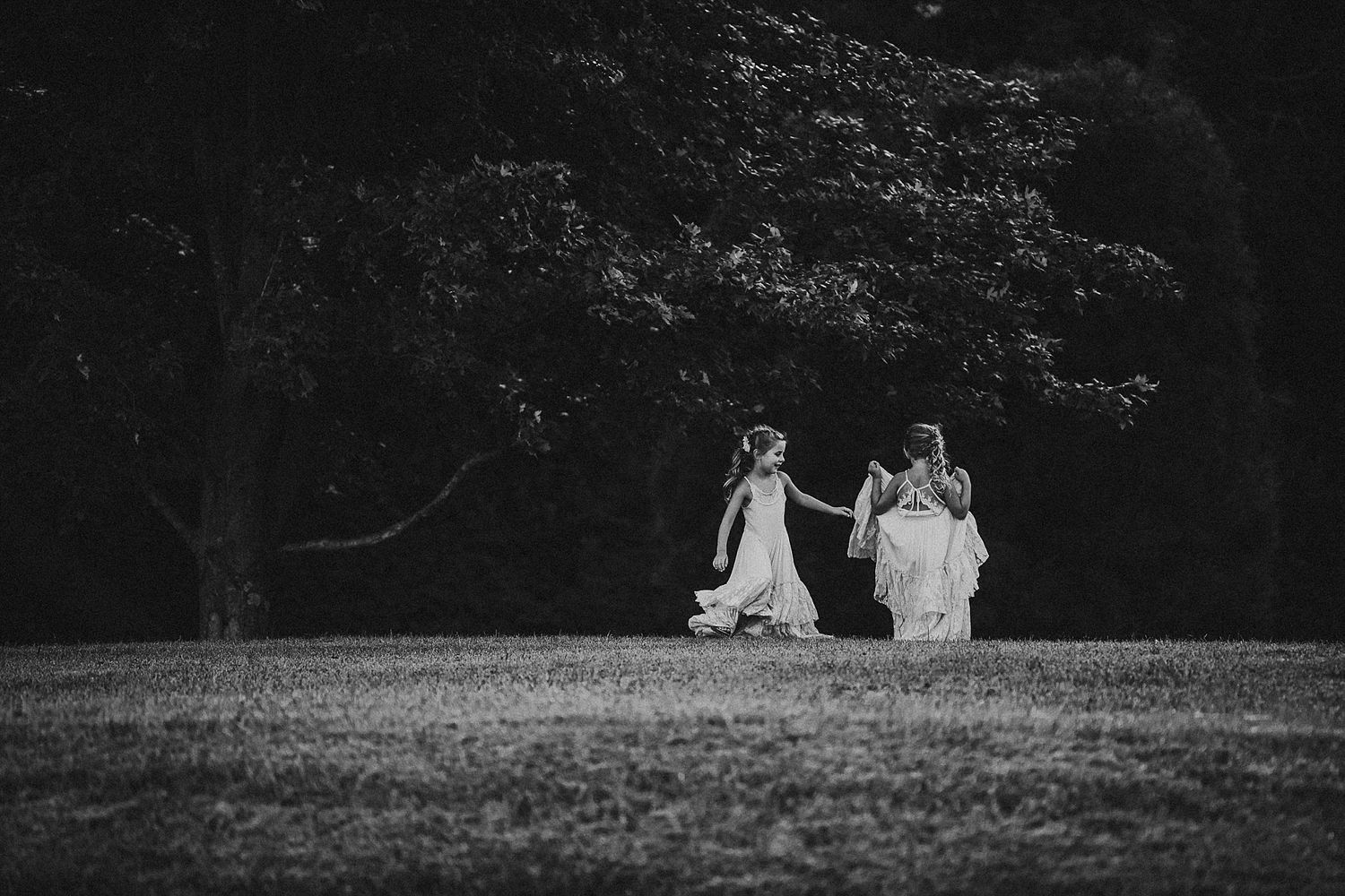 Black and white image of people sitting together on a hilltop under trees.