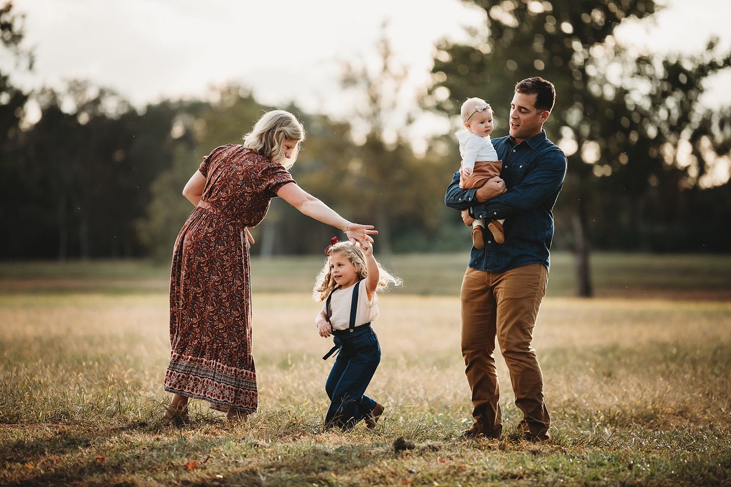 Family playing together in a field during golden hour sunset.