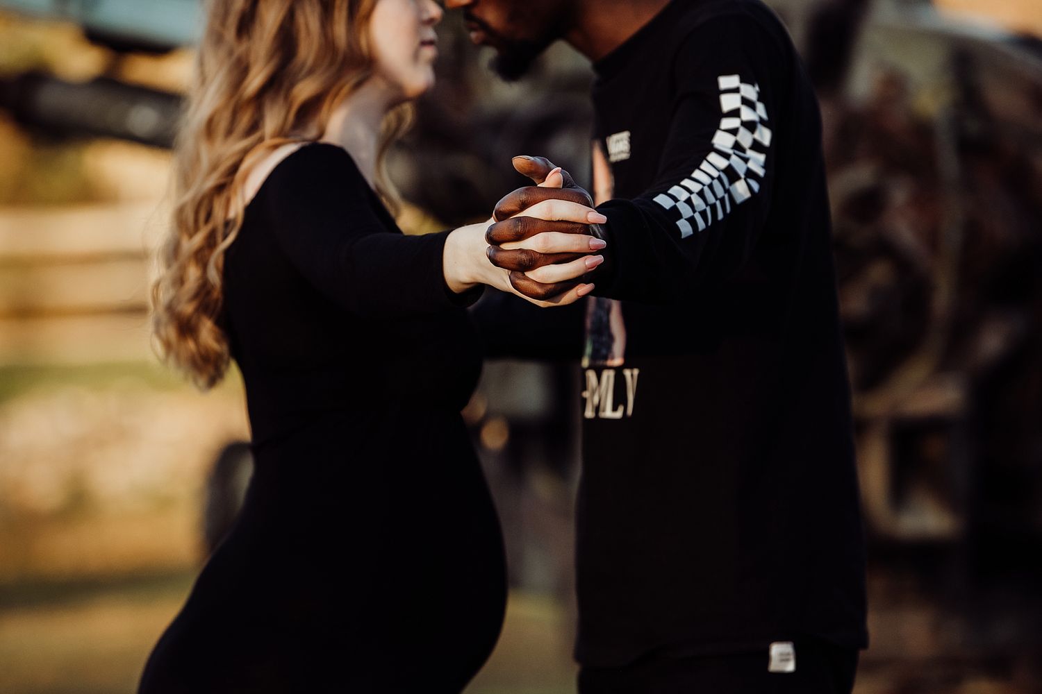 Close-up of couple holding hands while dancing outdoors.
