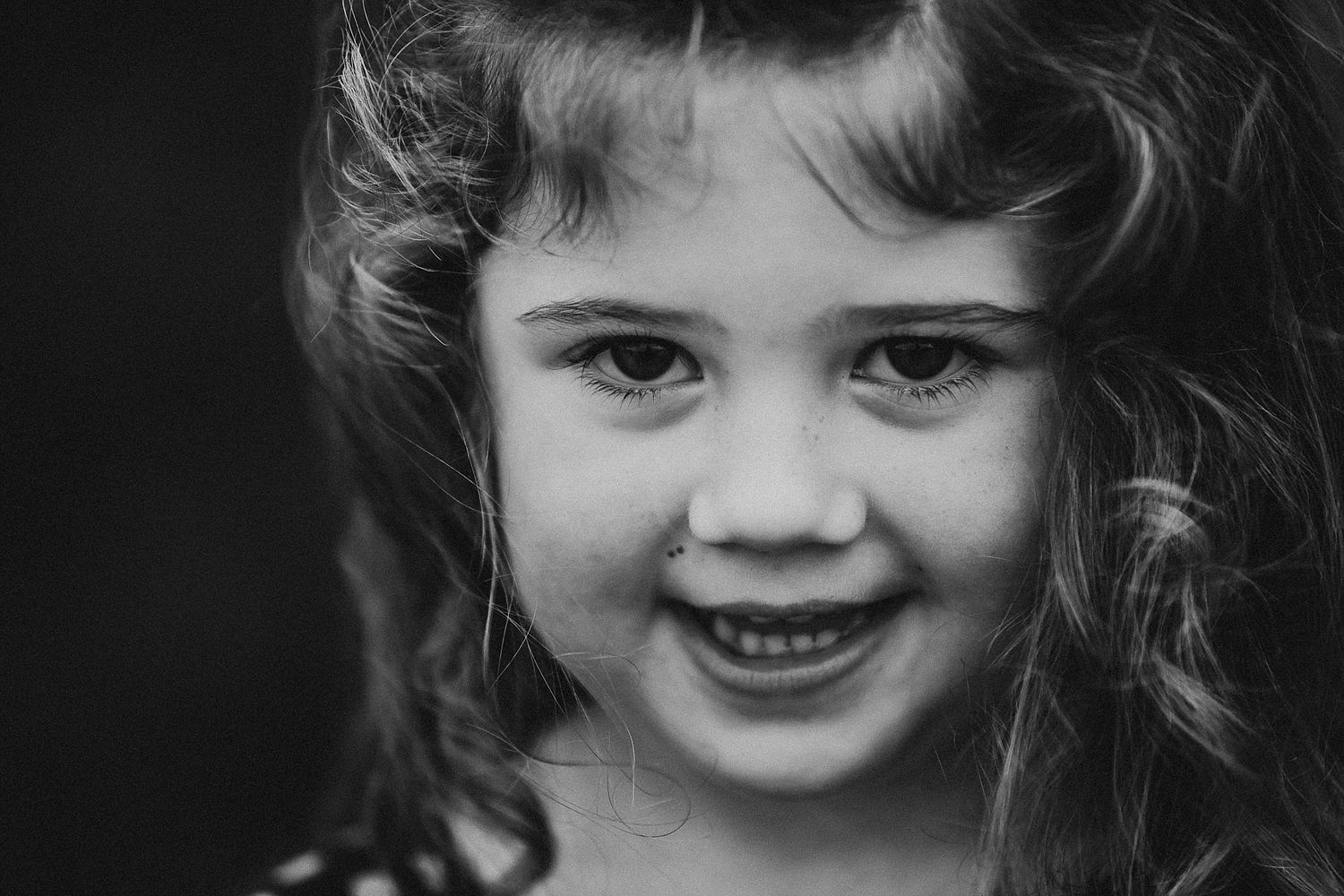 Black and white portrait showing joyful expression and curly hair.