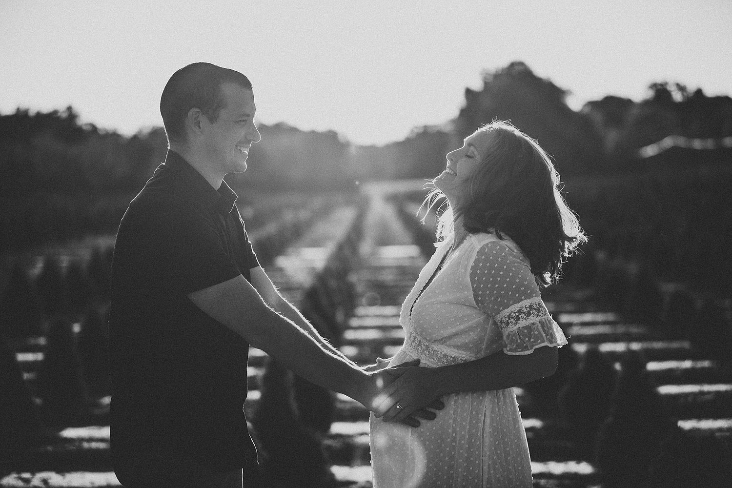 A couple shares an intimate moment while backlit by golden sunlight in a scenic outdoor setting.