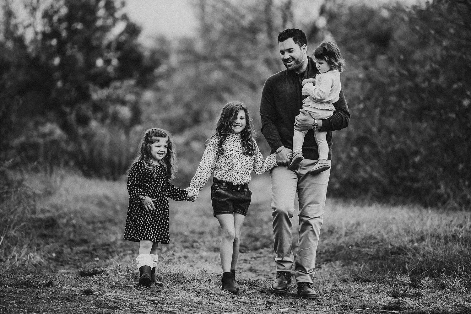 Family walking together on a trail in black and white candid portrait.