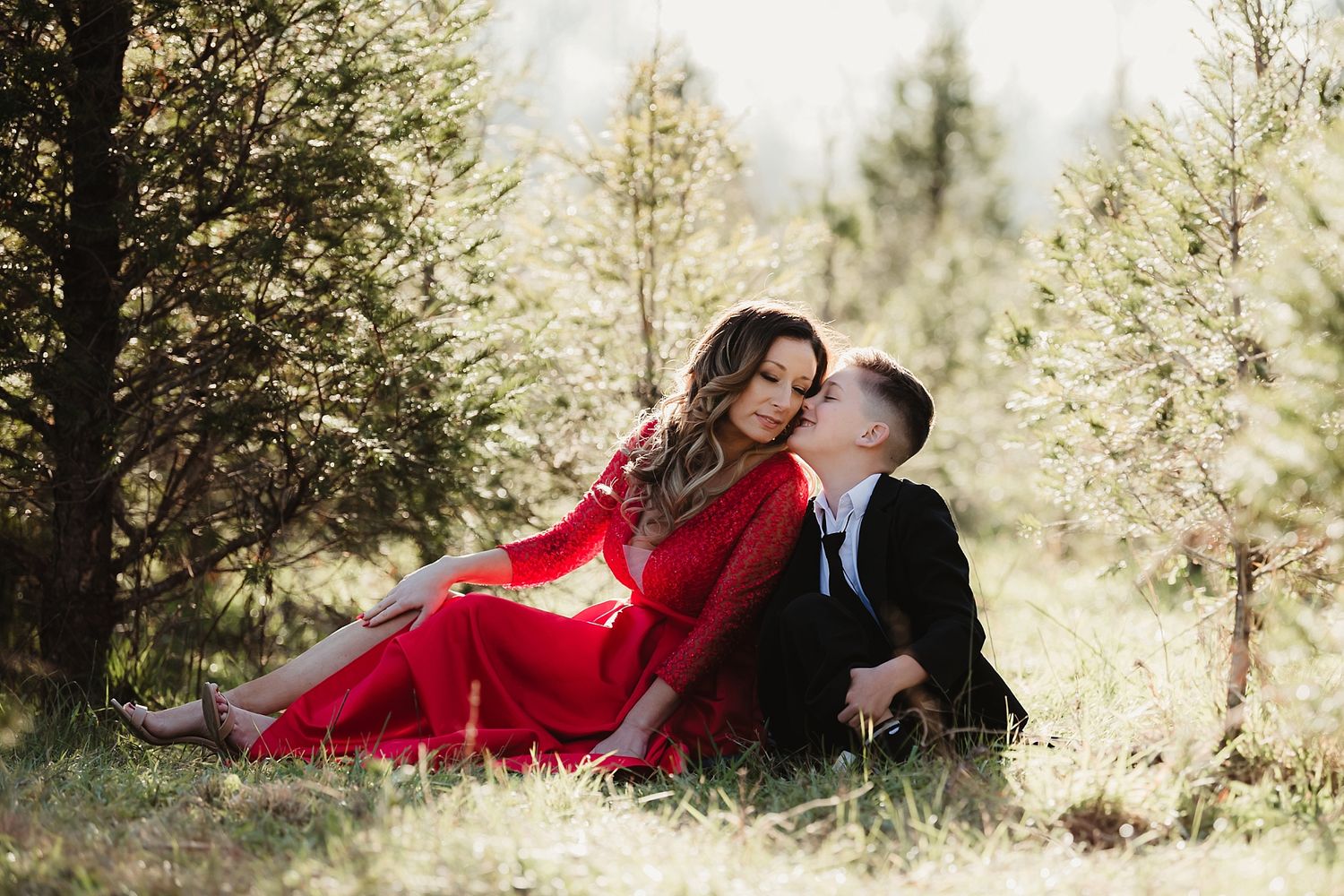 A romantic moment captured between two figures in a forest setting with soft natural lighting.