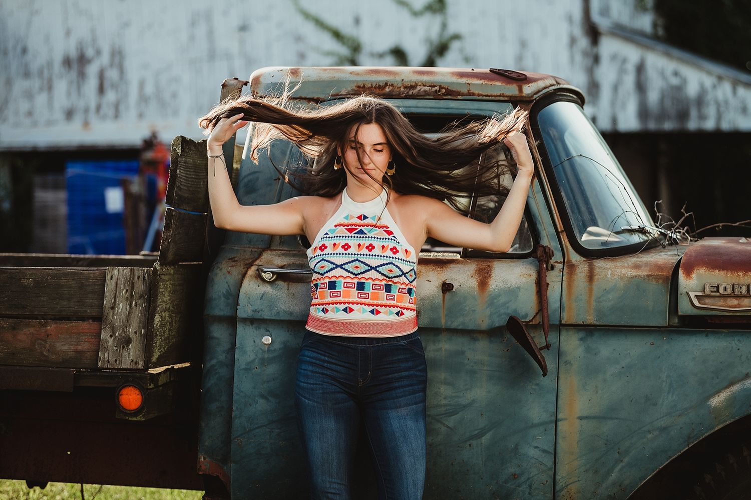 A playful pose beside a vintage blue truck while holding long flowing hair.